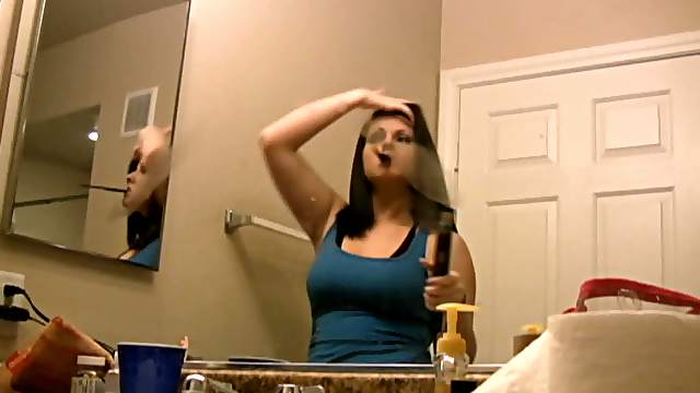 Pretty brunette babe straightens her hair in front of mirror